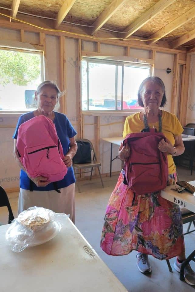 Two Navajo women holding donated backpacks
