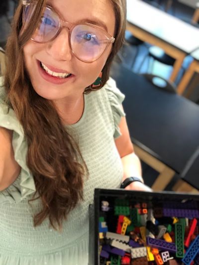 Selfie of female Engineering teacher, posing in her classroom with a basket of Legos