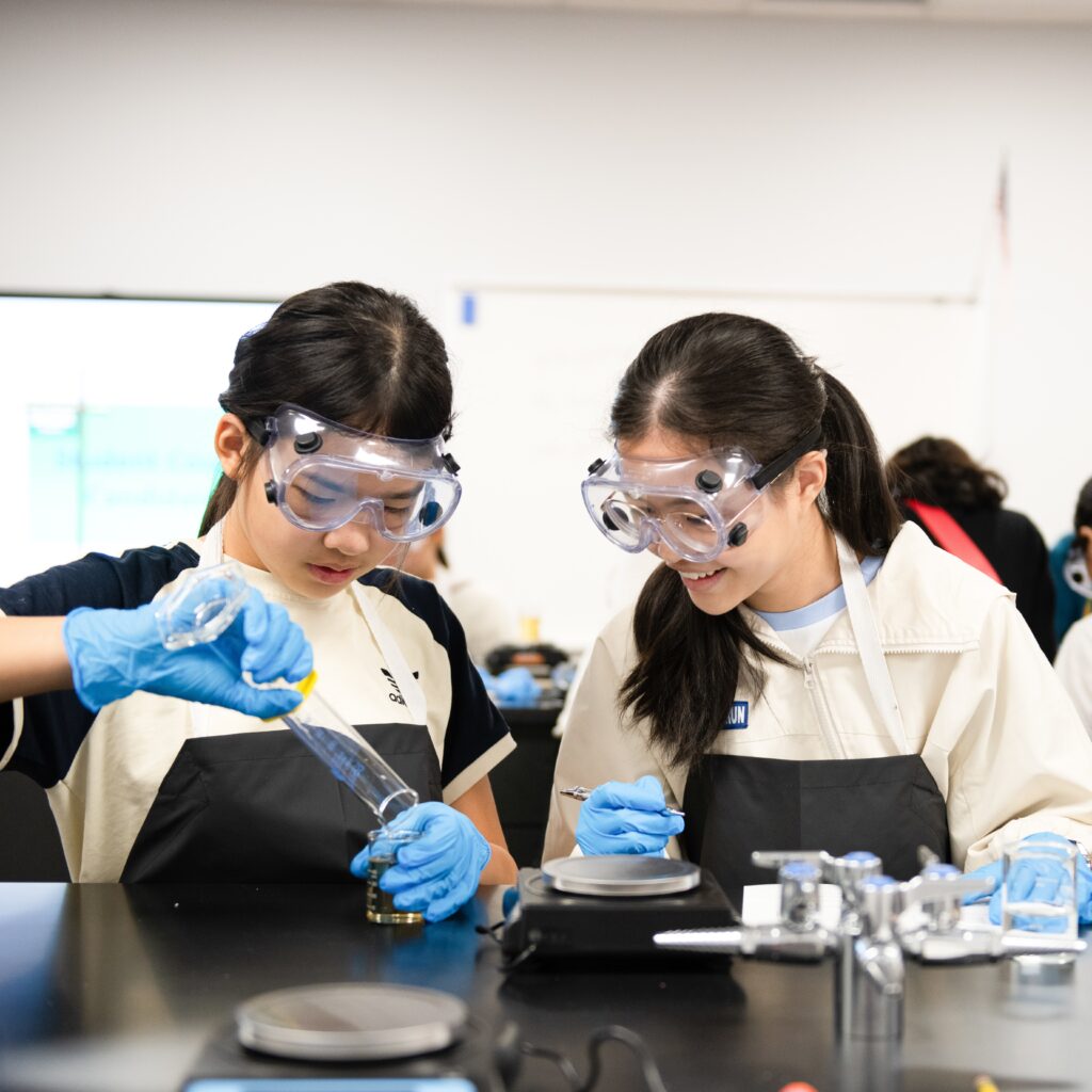 Two students wearing science class gear work on an experiment