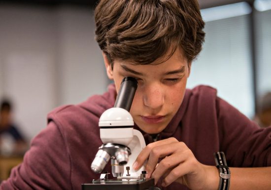 Male student looking through a microscope