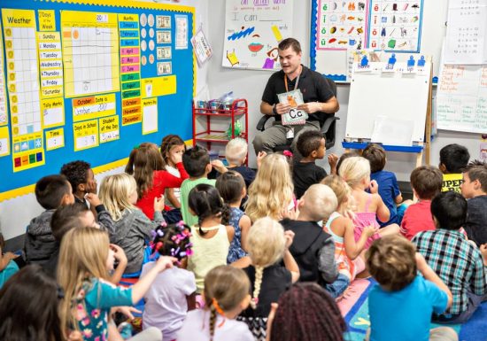 Male teacher reading to classroom of young students