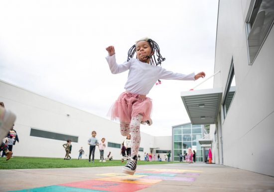 Young girl playing hopscotch outside