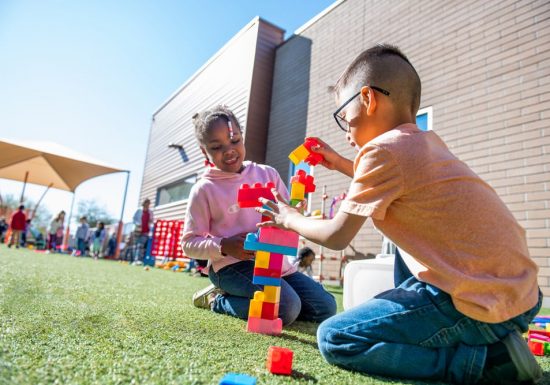 A young boy and girl playing outside with blocks